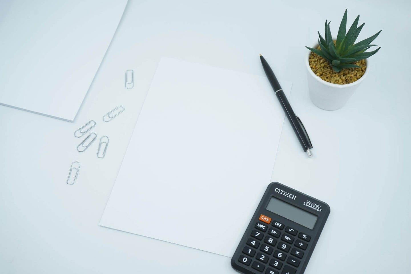 Calculator, pen and paper on a white desk Calculator, pen and paper on a white desk